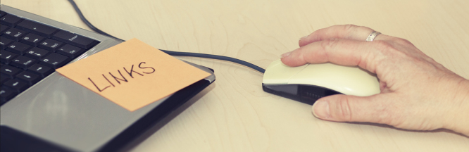 Eine Hand liegt auf einer Maus und in der linken Bildecke ist  ein Teil der Tastatur eines Laptops zu erkennen 